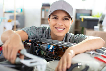 female engineer or tech repairs electronic deviceの写真素材