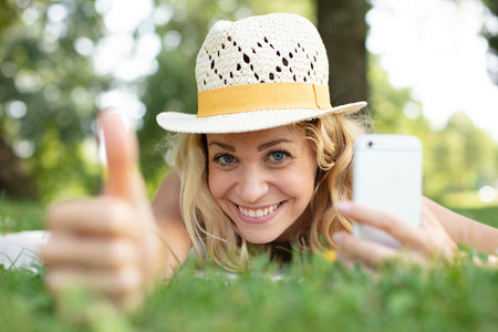 beautiful woman lying on the grass thumb up
