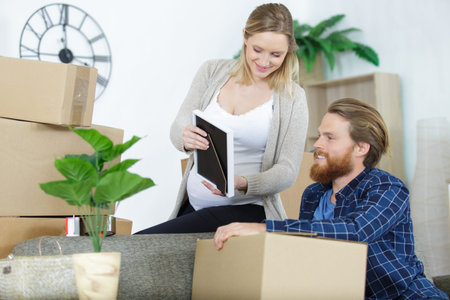 happy pregnant woman checking old picture while moving boxes
