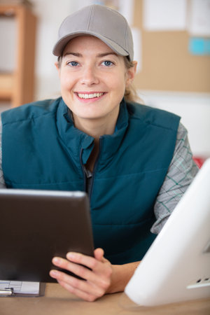female technician at workbench holding a digital tablet