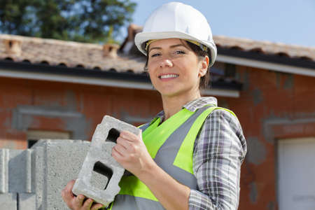 woman builder holding a brick wallの写真素材