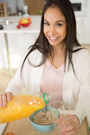 young woman pouring orange juiceの写真素材