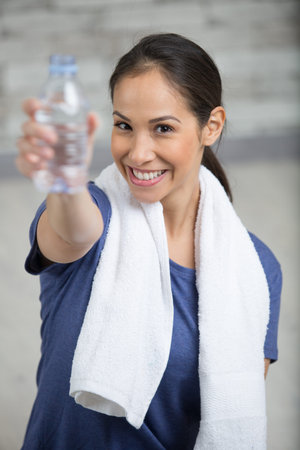 woman in sport wear with water at gym