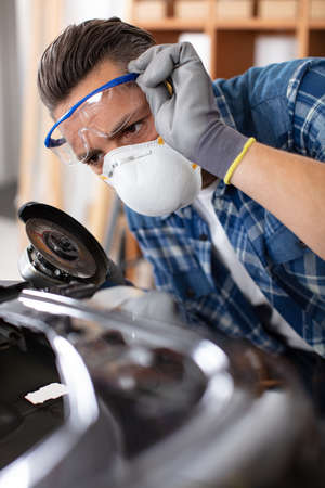 mechanic wearing dust mask using an angle grinderの写真素材