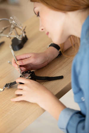 a female is holding tweezers to repair vintage clocksの写真素材
