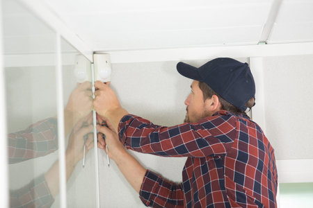 technician installing an alarm on ceiling indoorsの写真素材