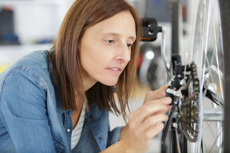woman repairing bicycle in workshopの写真素材