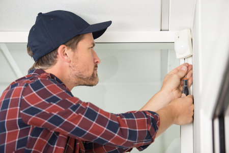 electrician installs alarm on the wall