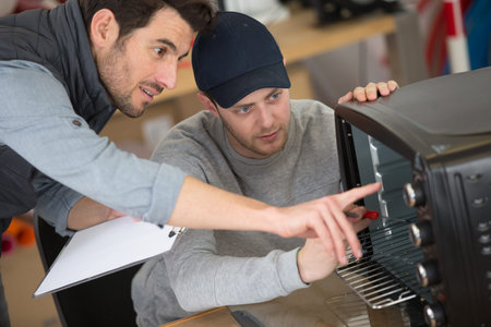 apprentice engineer learning how to repair oven