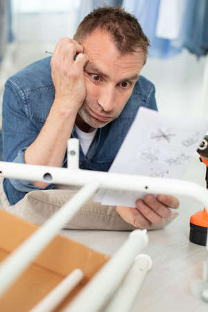 shocked young man confused about assembling furnitureの写真素材