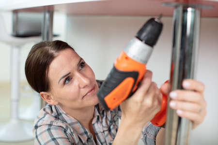 female contractor repairing furniture at homeの写真素材