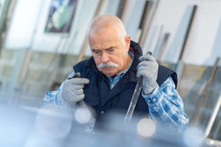 elderly worker watches processing of detail on milling machineの写真素材