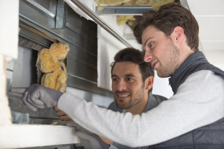 two men working with foiled insulation on the window sill