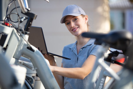 woman with laptop checking row of rental bicycles