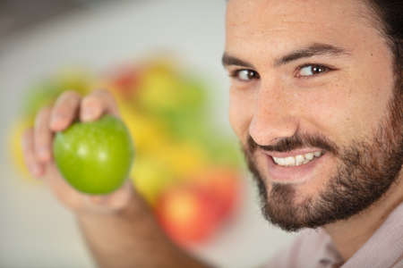 young cheerful man showing appleの写真素材