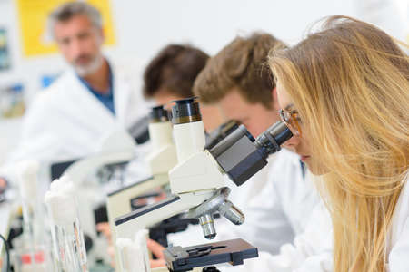 Science students looking into microscopesの写真素材