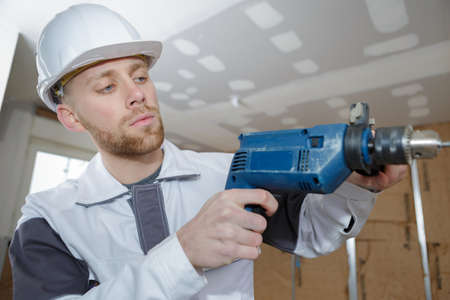 man drilling the wall with drill perforatorの写真素材
