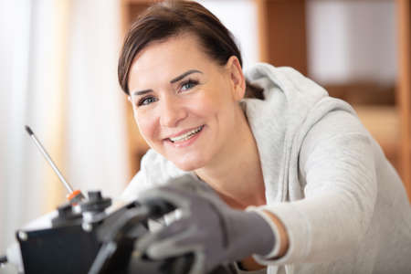 happy female builder with screwdriver fixing socket indoorsの写真素材