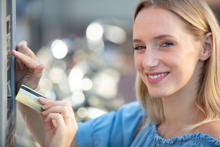 woman in blue at automatic payment machine using card
