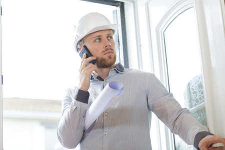 successful male architect in helmet talking mobile phoneの写真素材