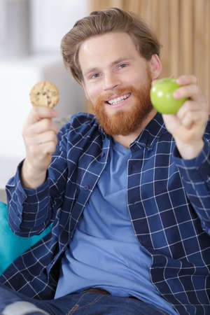 happy man holding an apple and a cakeの写真素材