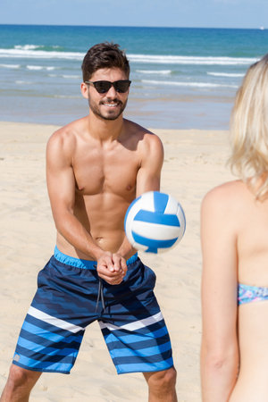young couple playing volleyball on the beachの写真素材