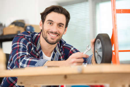 young male technician repairing cart wheelの写真素材