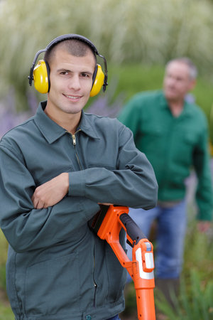 young smiling gardener with crossed arms standing in garden