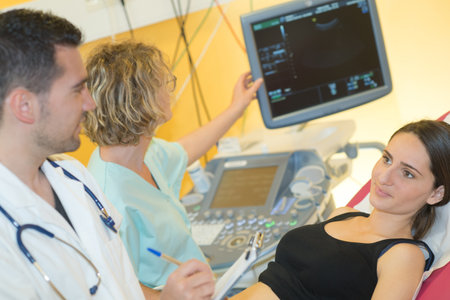 happy pregnant looking at an ultrasound with doctorsの写真素材