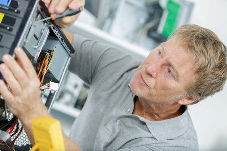 man is repairing broken pc with a screw driver