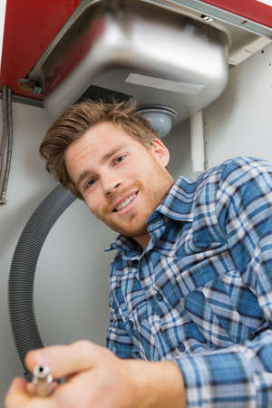 Portrait of plumber underneath sinkの写真素材
