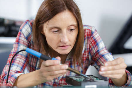 a female pc technician soldering pc partの写真素材