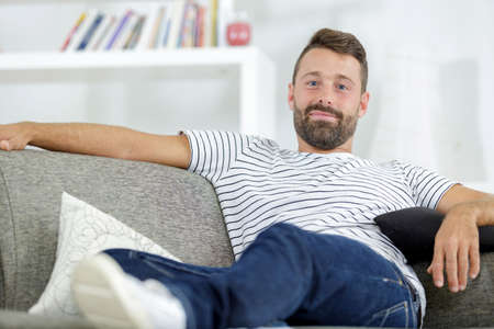 portrait of a casual man resting sitting on a couchの写真素材