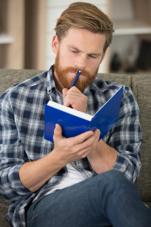 young hipster guy reading a book or note book