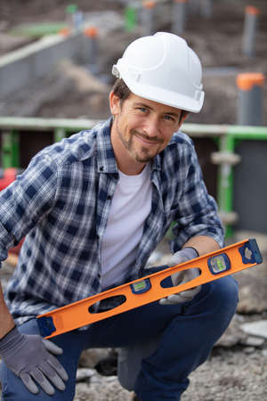 young handyman using spirit level outdoorsの写真素材