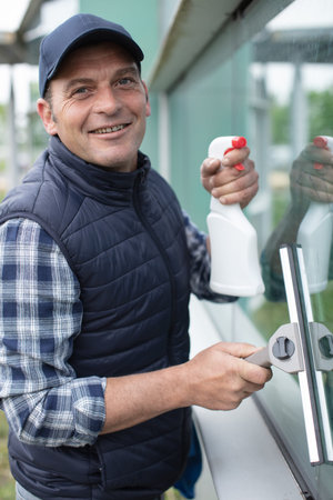 male worker washing window glass from outside