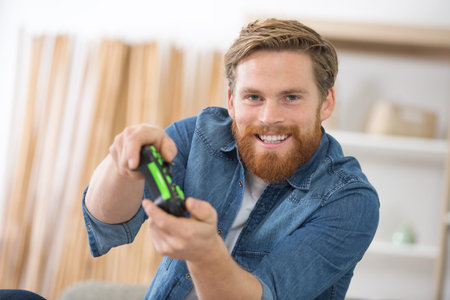 happy young man sitting on a sofa playing video game