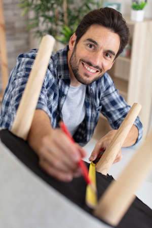 repairman measures new chair at homeの写真素材