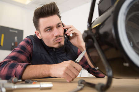 young technician working on broken computer in his officeの写真素材