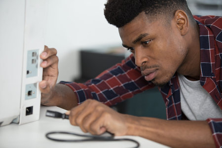 man inserting power lead into computer