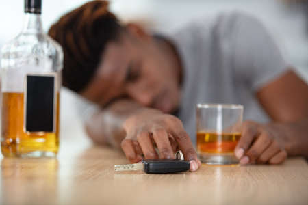 man hand holding car keys over whiskey glassの写真素材