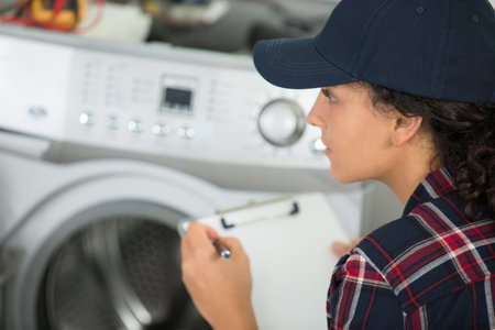 female plumber with clipboard near washing machine