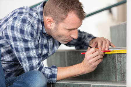 young worker using tape measure for measuring staircasesの写真素材
