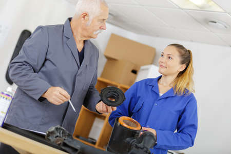 female mechanic apprentice with teacher looking at partsの写真素材