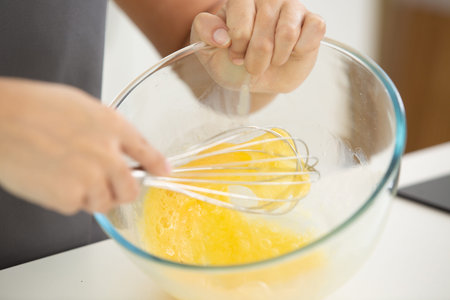 female chef beating eggs with wire whisk in bowl