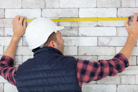 professional handyman measuring length of brick effect wallの写真素材