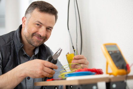 male electrician holding pliers and working on wiring