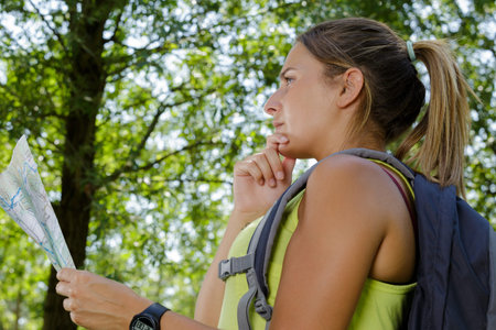 woman with backpack in countryside looking at map