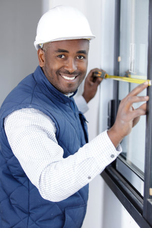 builder measuring a window using a tape measure and pencil