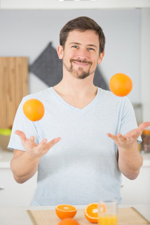 playful man with orangesの写真素材